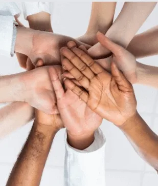 A circle of hands from a diverse group of people placed on top of one another